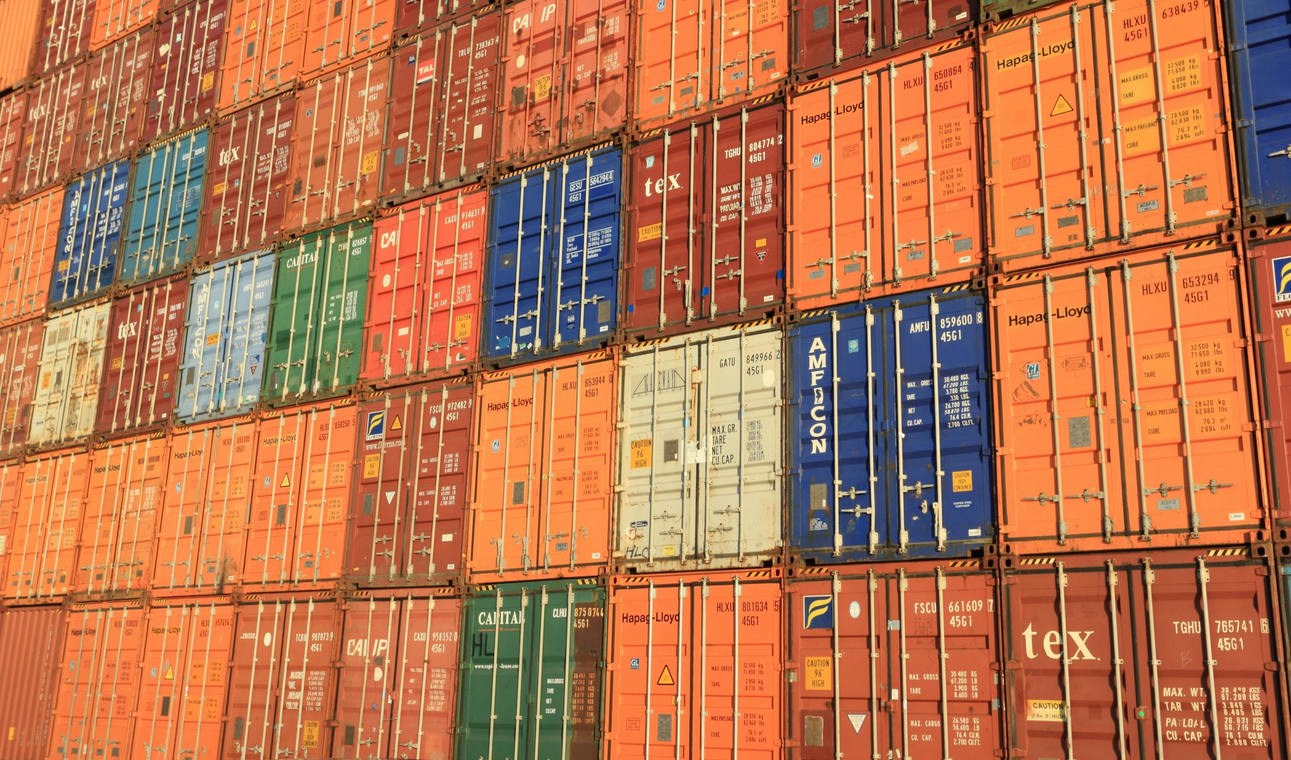 A close up of a stack of shipping containers - orange, red, blue, green and brown