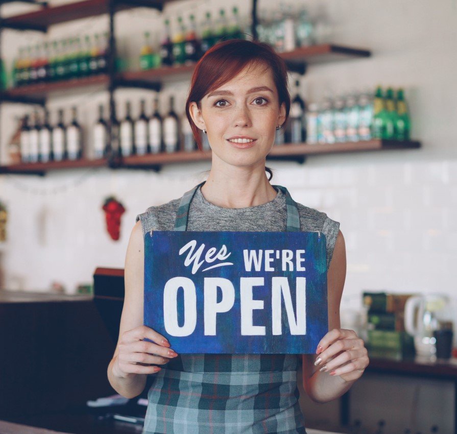 Small business owner holding an Open sign
